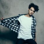 Confident man in checkered shirt posing naturally for a photo shoot, demonstrating how men learn to pose for photos.