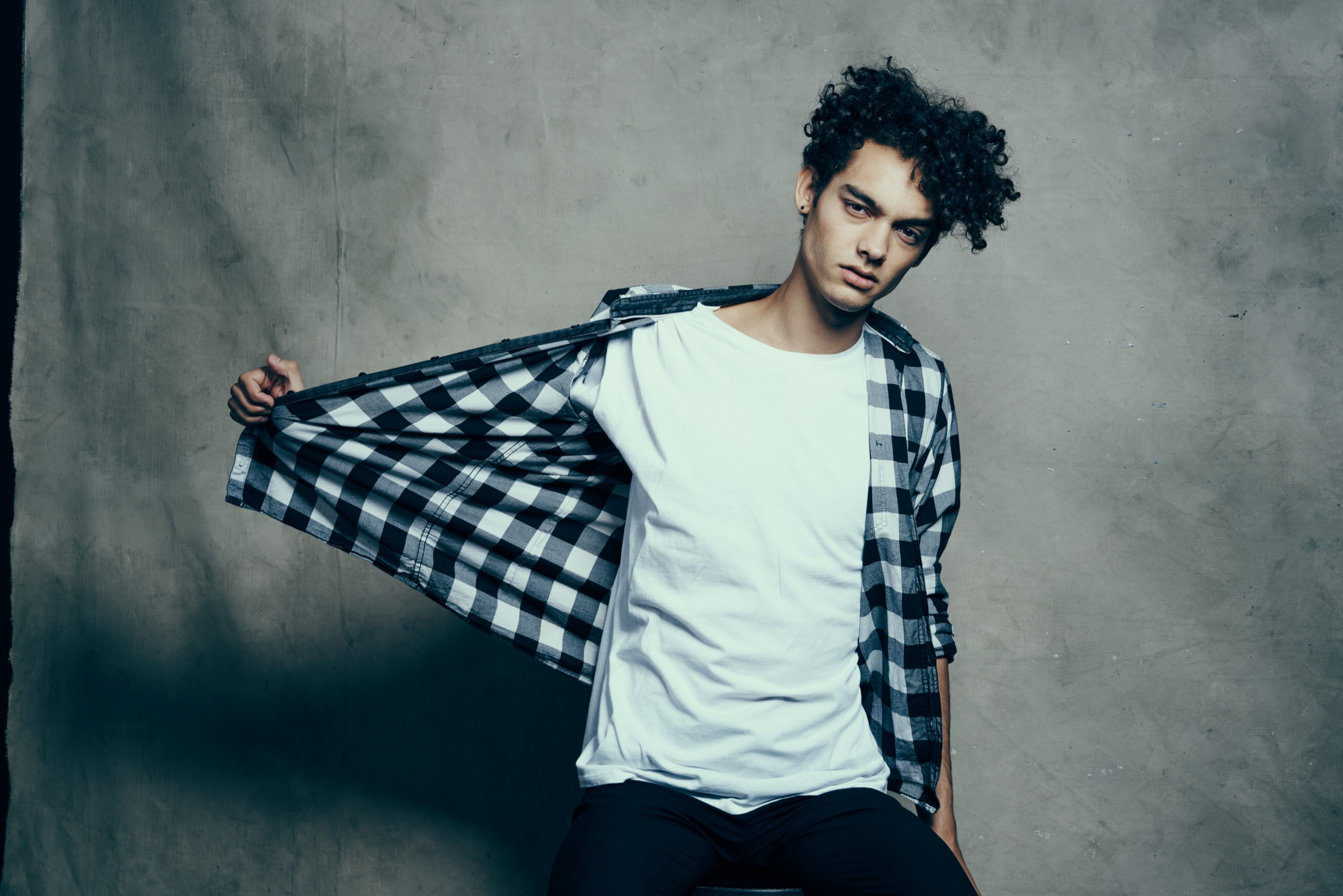 Confident man in checkered shirt posing naturally for a photo shoot, demonstrating how men learn to pose for photos.