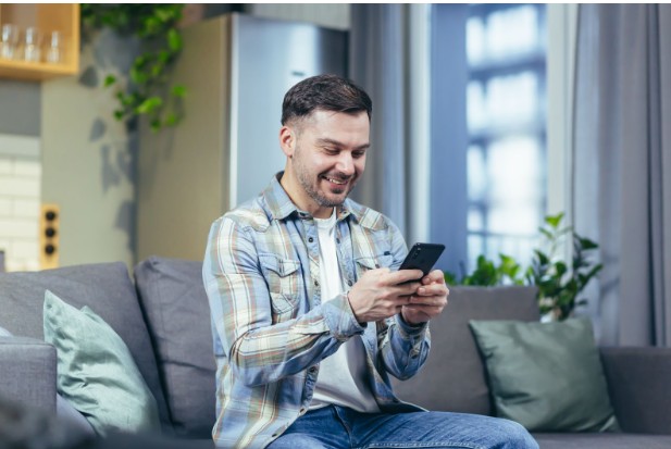 A person comfortably using a smartphone at home while sitting on a couch.