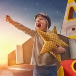 Child in astronaut costume playing outside at sunset