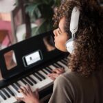 Woman playing piano with Bluetooth headphones for online learning