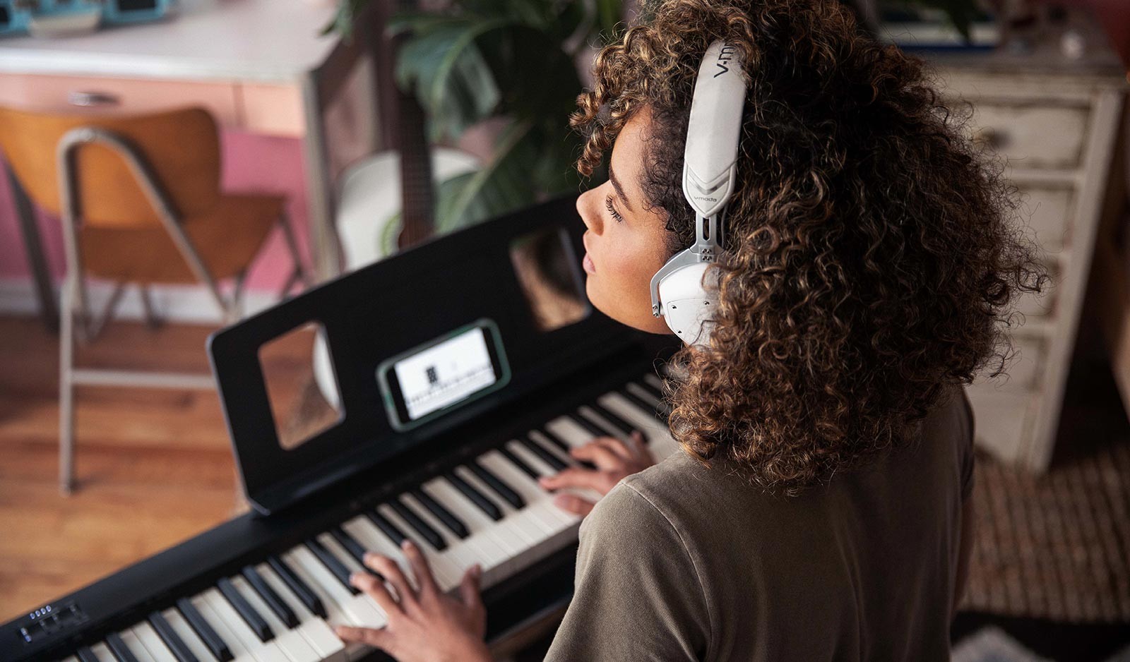 Woman playing piano with Bluetooth headphones for online learning