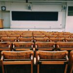 Empty lecture hall with rows of wooden benches, symbolizing the limitations of formal language classes in achieving fluency.