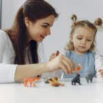 A teacher engaging with a child in a classroom setting, showcasing playful learning.