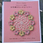 Close-up of a Japanese craft book cover featuring delicate doily patterns and pink floral designs