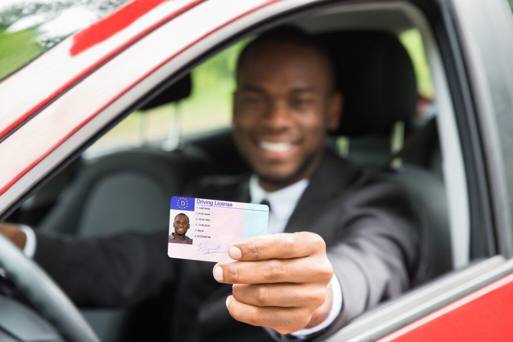 Young man showing his drivers license: Driving age by state and GDL programs