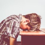 A young adult experiencing learned helplessness and hopelessness, feeling overwhelmed and unable to cope with challenges.