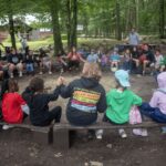 Campers in a circle holding hands, symbolizing community and outdoor learning adventures at Hale.