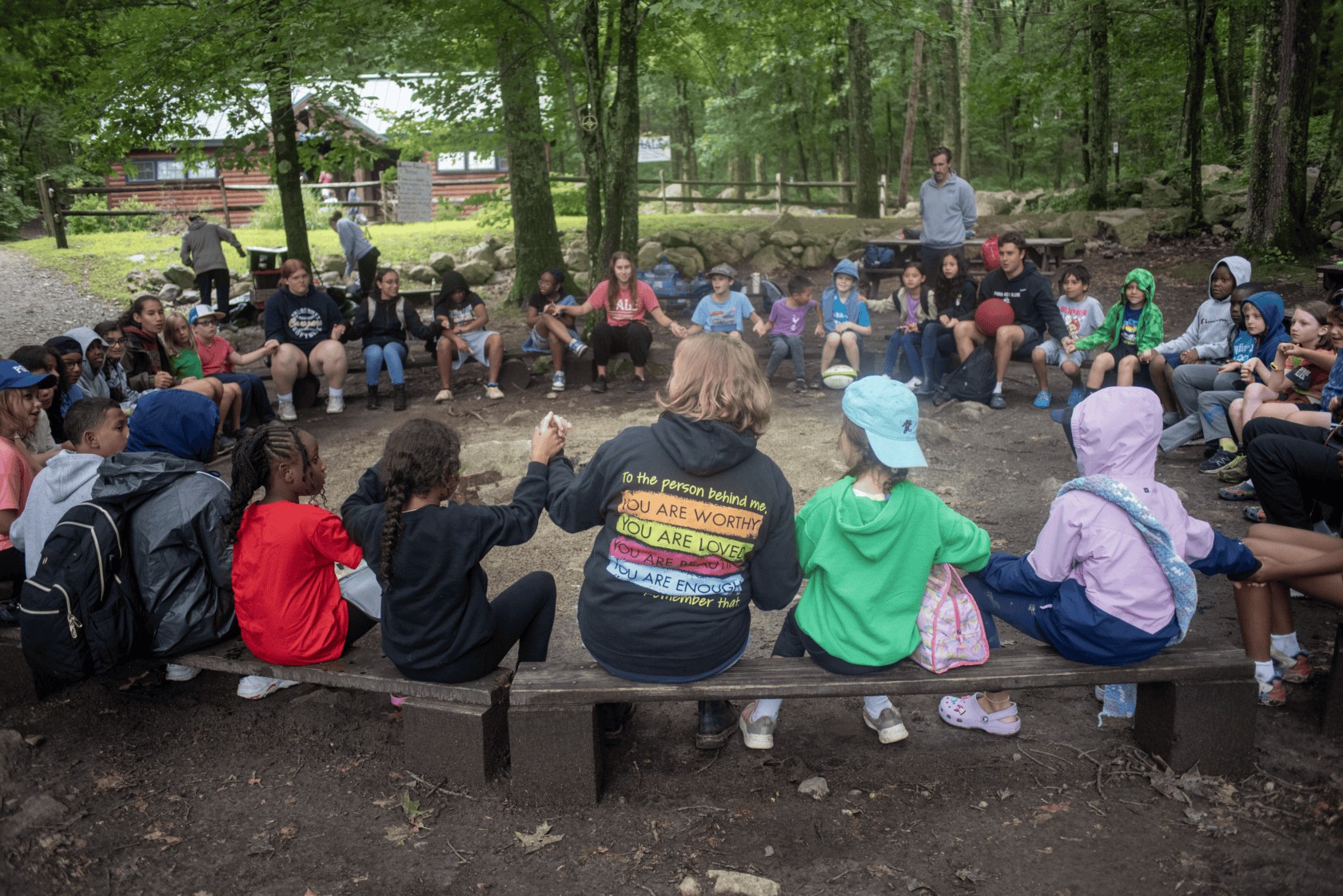 Campers in a circle holding hands, symbolizing community and outdoor learning adventures at Hale.