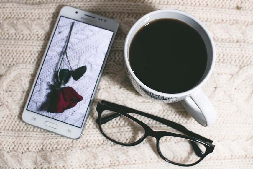 A phone, a pair of glasses and a cup of coffee, arranged on a table to illustrate spatial relationships.