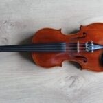 A violin resting on a white surface, showcasing its elegant curves and strings