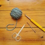 Essential crochet supplies: yarn, hook, yarn needle, and scissors.