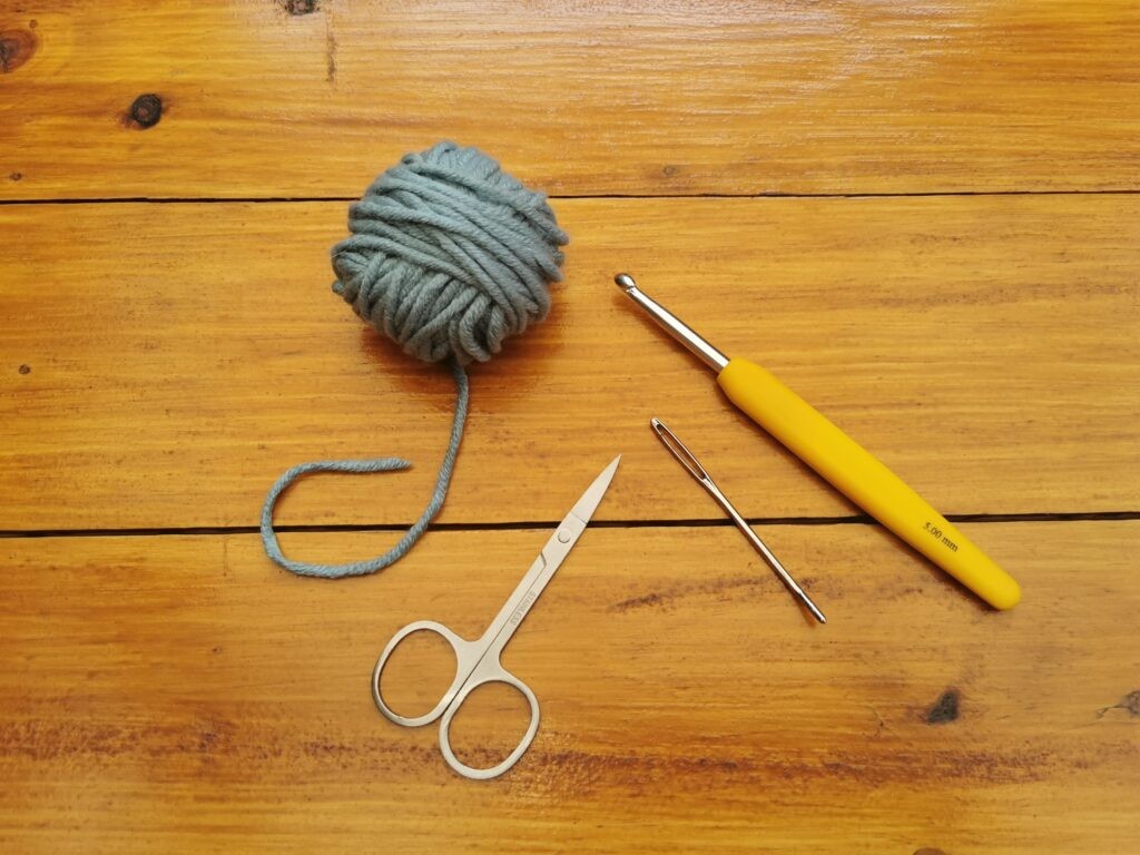 Essential crochet supplies: yarn, hook, darning needle, and scissors