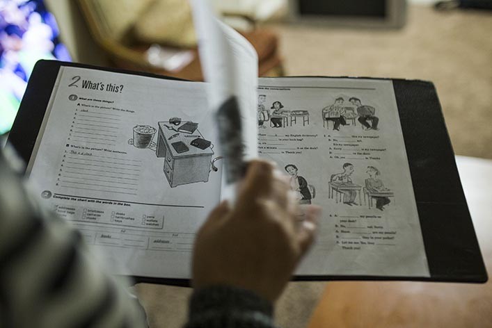 A student engrossed in a language-learning workbook, highlighting the dedication required to learn English.