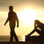 Couple silhouette breaking up a relation on the beach at sunset