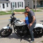 Man and son on white Yamaha Bolt motorcycle, parked in a driveway