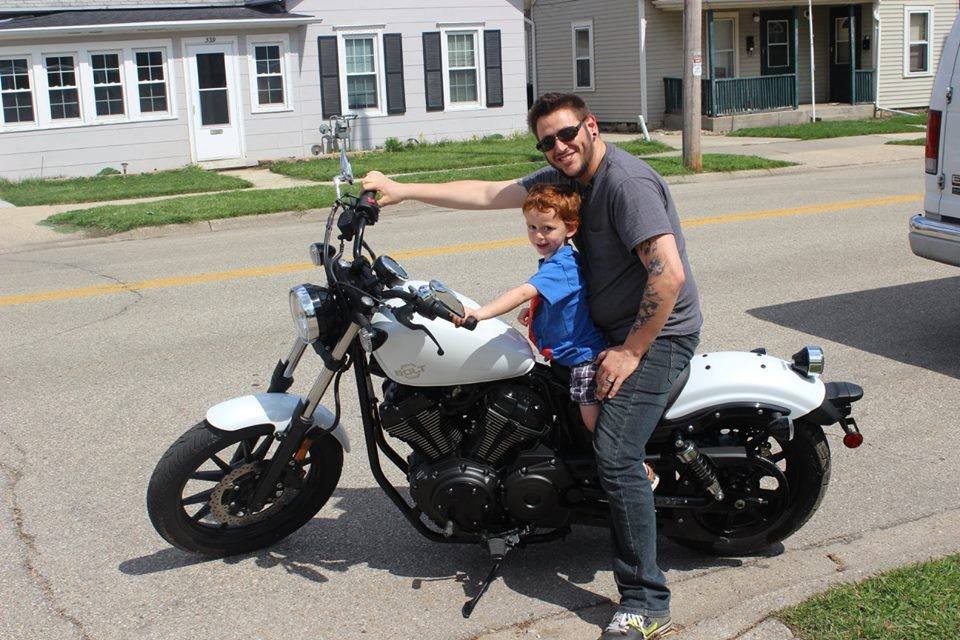 Man and son on white Yamaha Bolt motorcycle, parked in a driveway