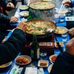 A vibrant table setting with Korean dishes, hands poised to enjoy the meal.