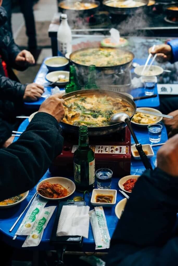 A vibrant table setting with Korean dishes, hands poised to enjoy the meal.