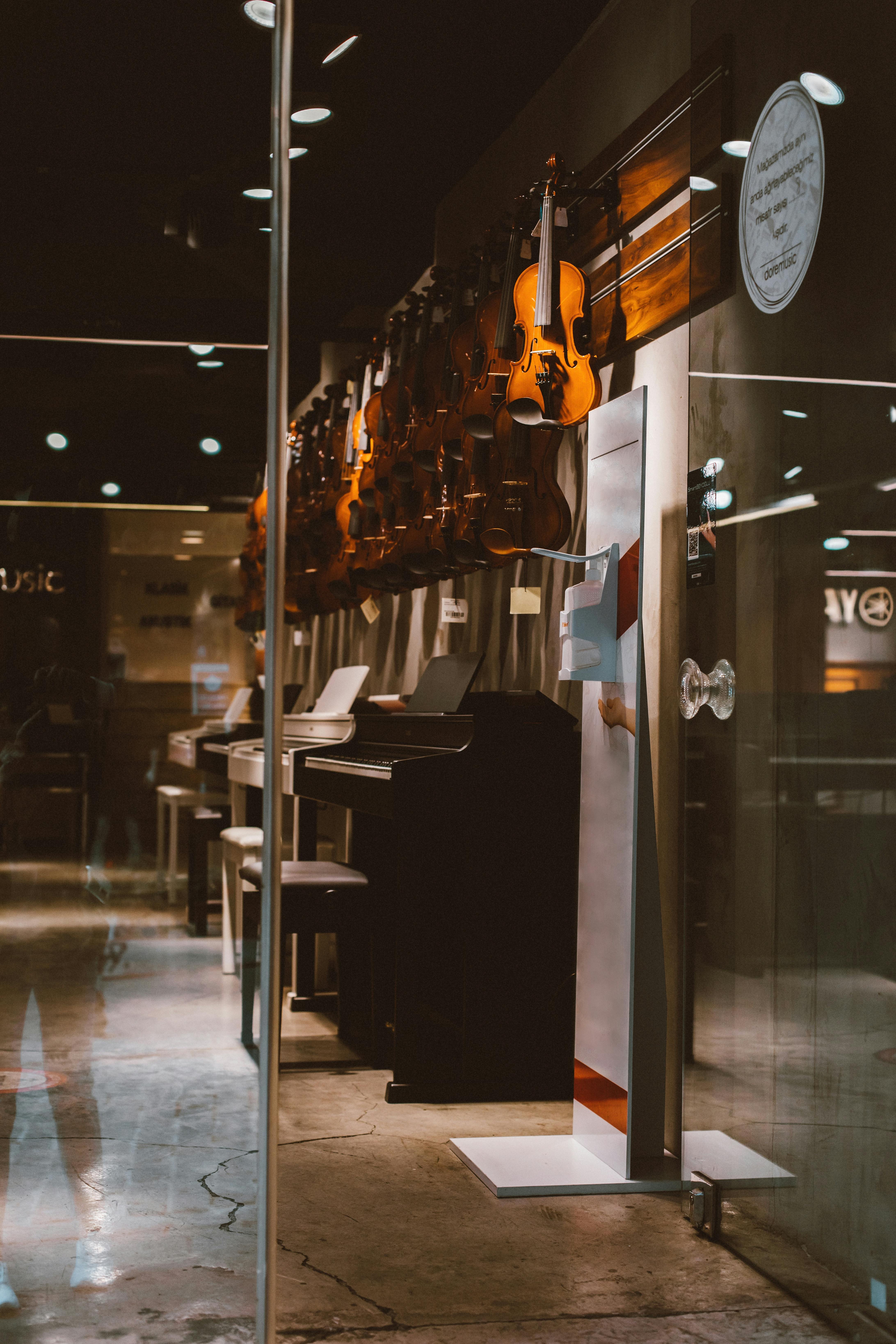 Glass door open to a music store showcasing upright pianos and violins, emphasizing the importance of choosing the right instrument for learning piano.