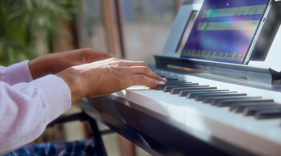 Practicing keyboard lessons using the Simply Piano app, learning notes and chords.