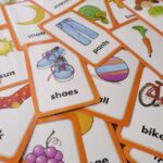 Flashcards with pictures of daily items and their name in English are spread on a table