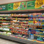 Shelves of meal deal options in Morrisons supermarket, UK. Full fridges filled with soft drinks and packaged sandwiches and salads.