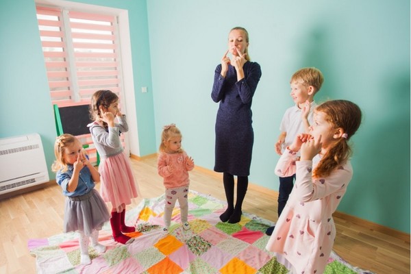 Preschool teacher and children singing learning songs in a classroom setting