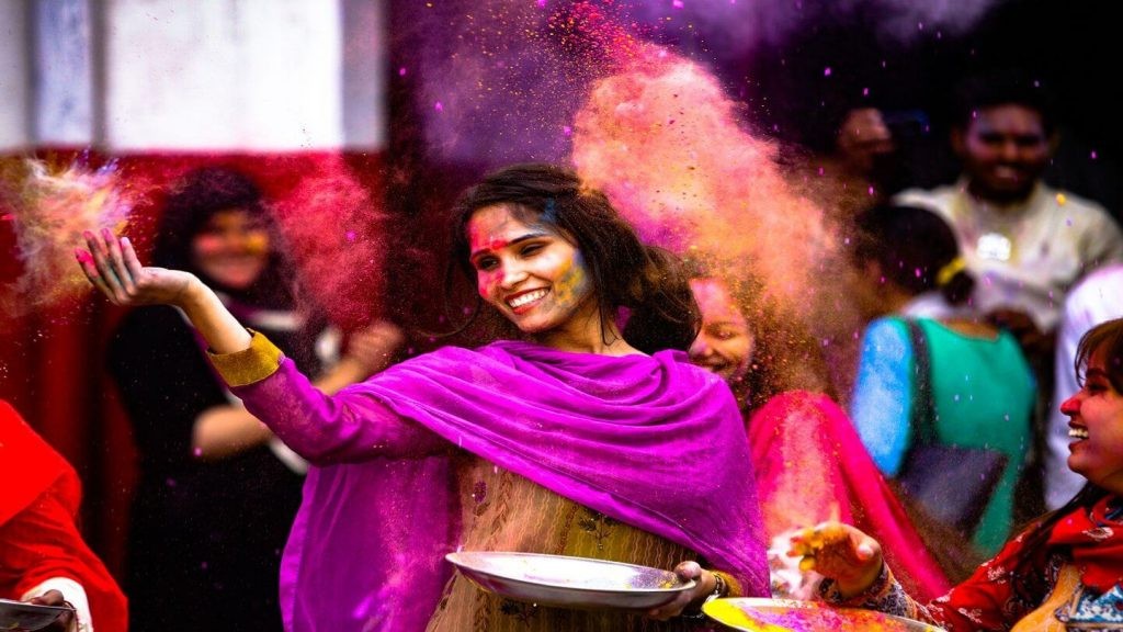 Woman throwing colored powder during Holi celebrations in India, celebrating cultural immersion.