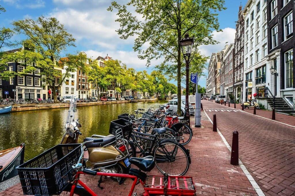 A row of colorful Dutch houses is reflected in the water.