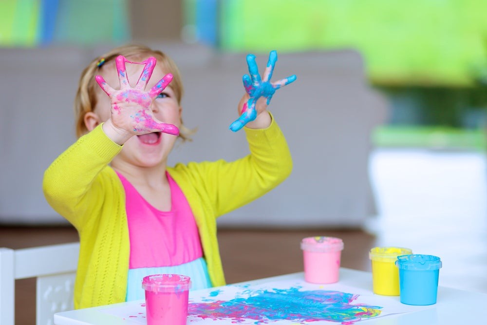 A child immersed in color mixing, engaging senses and promoting hands-on learning