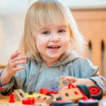 Toddler enthusiastically playing with colorful building blocks, showcasing joy and engagement in learning