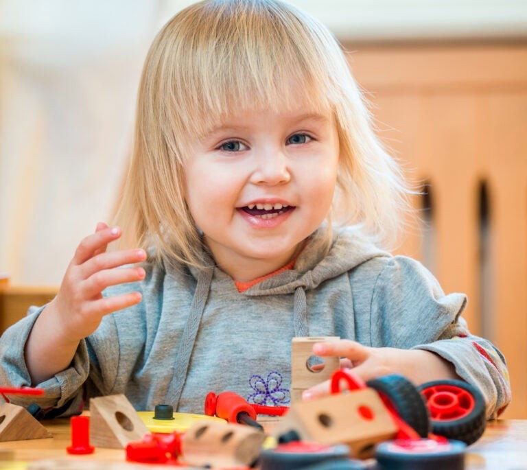 Toddler enthusiastically playing with colorful building blocks, showcasing joy and engagement in learning