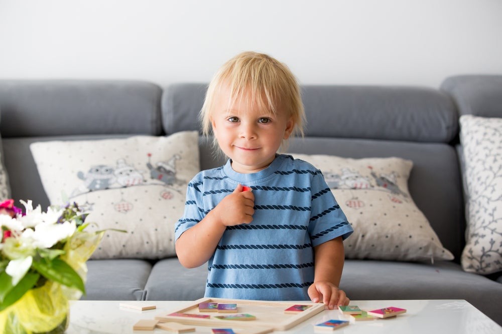 A toddler absorbed in solving a mini-tangram puzzle, demonstrating problem-solving skills and cognitive development