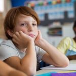 Boy sitting in class, looking deep in thought