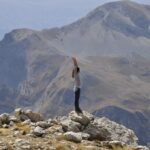woman standing on a mountain top, feeling free and empowered with self-love