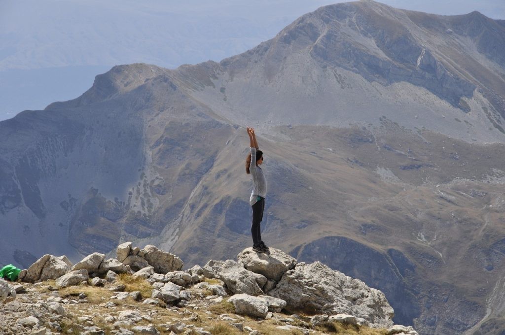 woman standing on a mountain top, feeling free and empowered with self-love