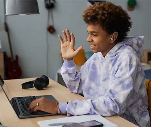 Happy school boy greeting teacher on laptop