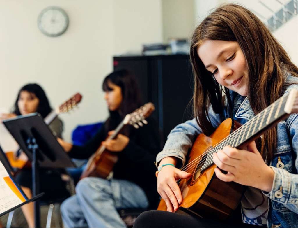 Smiling guitar student making music with others