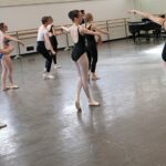 Ballet students practicing a combination by following the instructor, showcasing focused learning and guidance