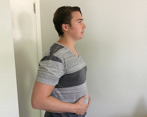 A person demonstrating diaphragmatic breathing with hands on their stomach, showing expansion and contraction
