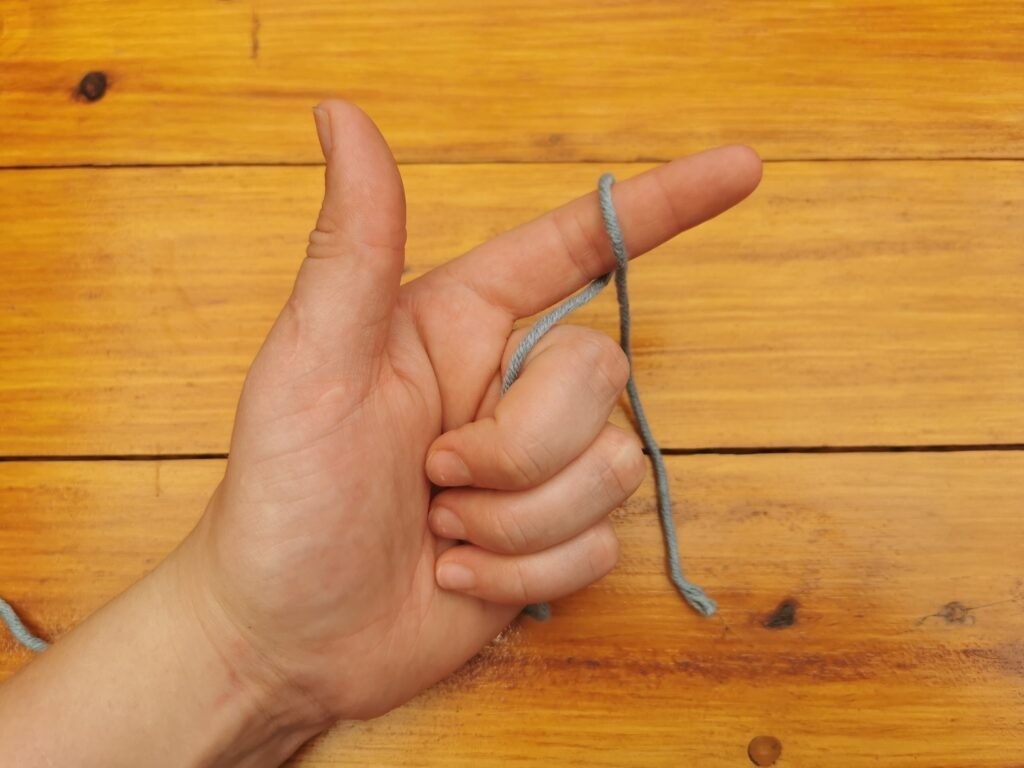 Wrap the yarn over your index finger with the short end at the front of your finger