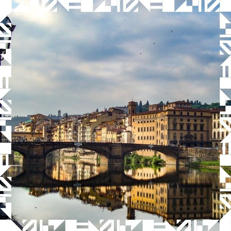 An Italian city with a river and bridge surrounded by buildings, showcasing the urban landscape and architecture