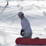 Woman enjoys a snowboarding session in the mountains, wearing protective gear and showcasing skillful control