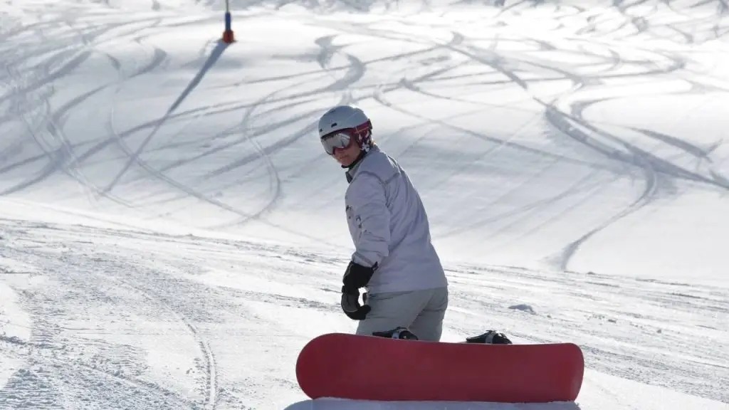 Woman enjoys a snowboarding session in the mountains, wearing protective gear and showcasing skillful control