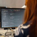 Woman using laptop at desk, focused on Codecademy interface