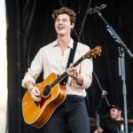 Young Shawn Mendes playing guitar, capturing the early stages of his music career fueled by social media and talent.