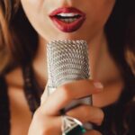 Close up of a person singing into a microphone, illustrating the importance of technique in singing in tune