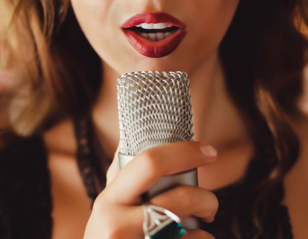 Close up of a person singing into a microphone, illustrating the importance of technique in singing in tune