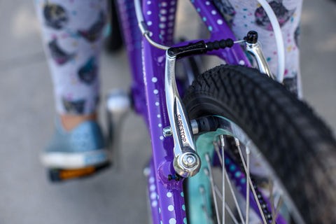 Child riding a bike with training wheels on a sunny day